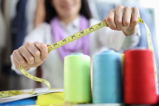 Seamstress holds tape measure in sewing workshop. Small business development concept and atelier opening