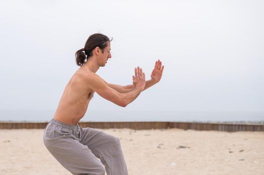 Caucasian man with long hair practicing qigong outdoors