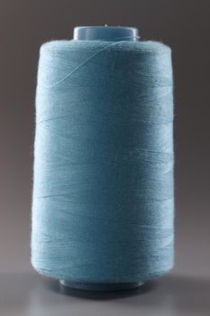 Texture of blue thread in sewing spool on gray background. closeup. Threads for sewing clothes.