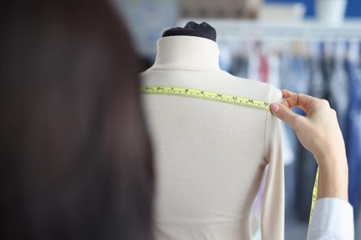 Fashion designer stylist takes measurements with centimeter from clothes on mannequin. Atelier services concept