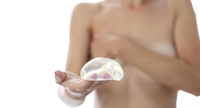 Woman holds silicone breast implant for breast augmentation. Plastic surgery concept