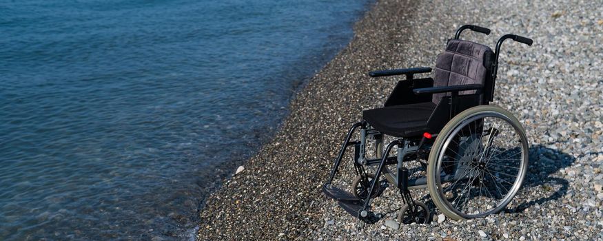 An empty wheelchair on a rocky seashore