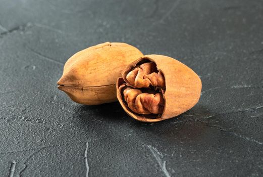 Inshell pecan with split half on dark concrete background