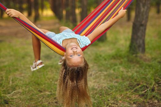Fun in the garden. lovely girl swinging in colorful hammock outdoor