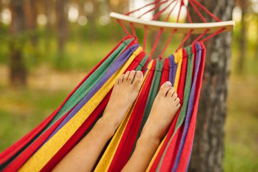 Foot of a child lying in the hammock and relaxing on a sunny day. Bare feet. Lifestyle concept.