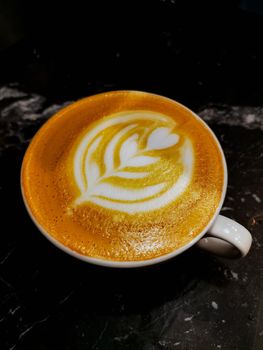 Tulip latte art on latte coffee in white cup on black marble table