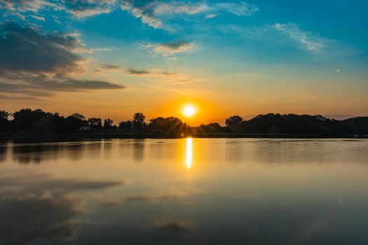 Beautiful rising sun over Odra river full of reflections in water and cloudy sky