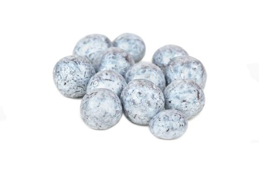 Heap of scattered candy hazelnuts in chocolate on a white background