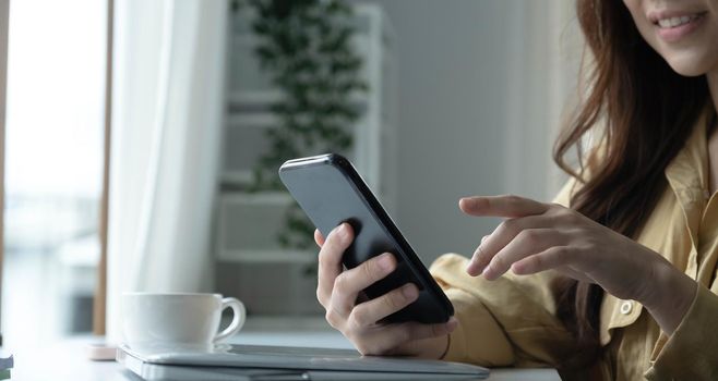 Close up hand of woman using smartphone at coffee shop cafe.