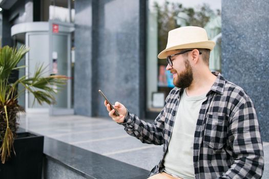 Smiling male tourist use smartphone during summer city break - technologies and social media app