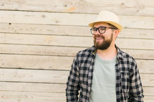 Laughing attractive man wearing hat over wooden background - emotion and vacation travel holidays