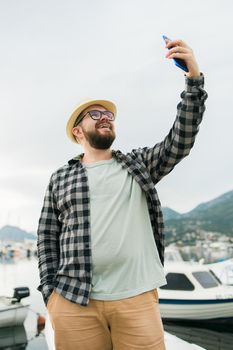 Traveller man taking selfie of luxury yachts marine during sunny day - travel and summer