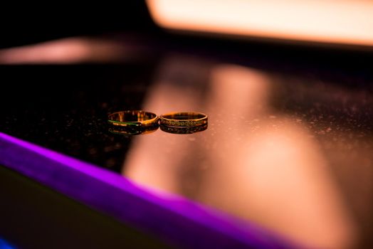 Two wedding rings on a mirror surface.