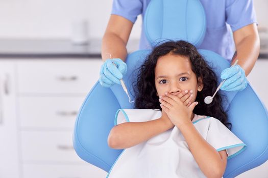 Shot of a young girl looking scared while having dental work done on her teeth.
