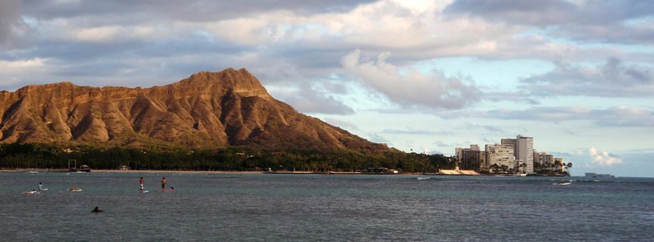 Diamondhead with surfers and Paddle boarders in the water and dramatic clouds