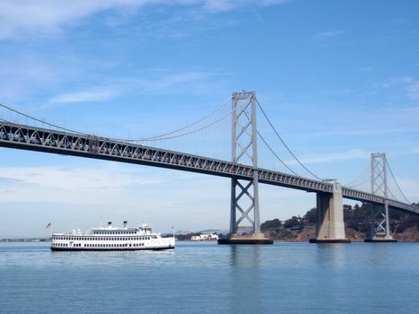 Hornblower Boat travels underneath the San Francisco Bay Bridge on a clear day