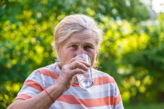 Grandmother drinks water from a glass. Selective focus. Drink.