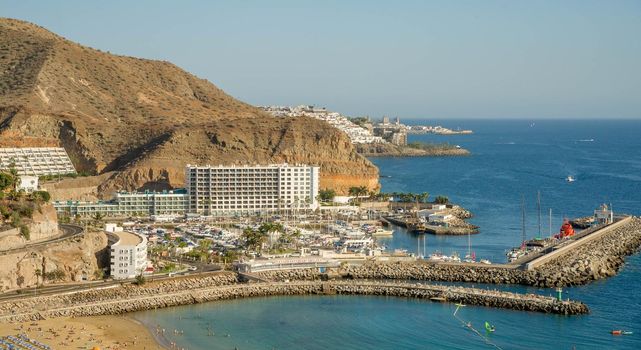 February 2 2022-Panoramic landscape with Puerto Rico village resort and beach on Gran Canaria Spain with yellow sand and volcanic mountains on the background