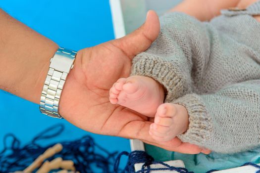 Newborn baby feet and hands of parents. Palms together.