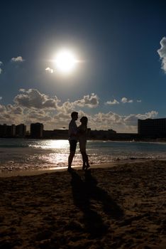 Silhouettes of men and women against the backdrop of the setting sun