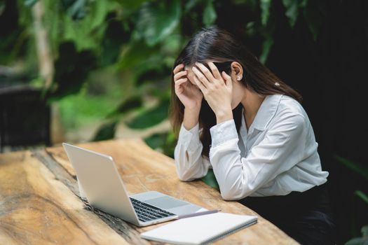 Asian business woman having stressful depression sad time working on laptop on wood table. Depression man sad serios working from anywhere.