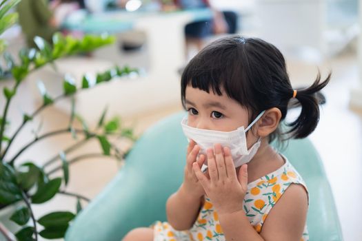 Asian girl wearing a mask sitting in the living room, Covid-19 situation prevention of covid health care Prevent infection with the covid 19 virus.