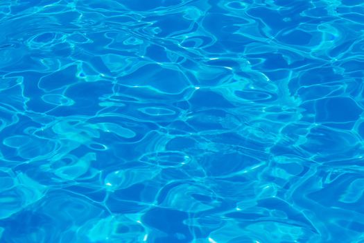 Swimming pool water surface with sparkling light reflections. Aqua background.