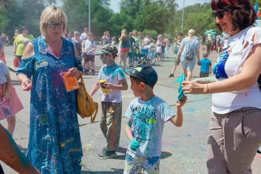 Novokuznetsk, Kemerovo region, Russia - June 12, 2022 :: Happy family with colorful faces painted with holi powder having fun outdoors.