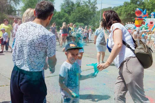 Novokuznetsk, Kemerovo region, Russia - June 12, 2022 :: Happy family with colorful faces painted with holi powder having fun outdoors.