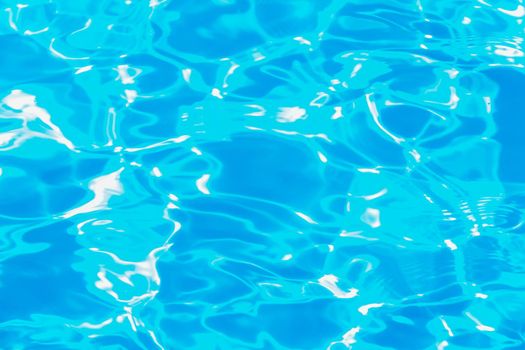 Swimming pool water surface with sparkling light reflections. Aqua background.