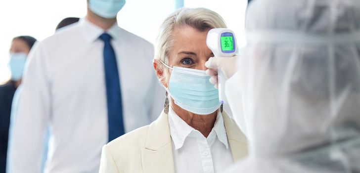 Shot of a group of businesspeople standing in a line to get their temperatures read.