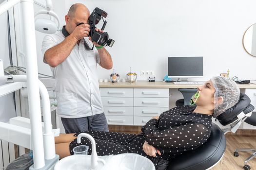 Dentist taking picture of mouth, his work on teeth of female patient