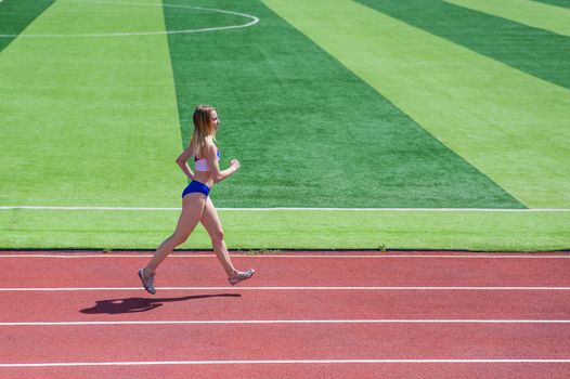 Young caucasian woman is engaged in jogging at the stadium outdoors