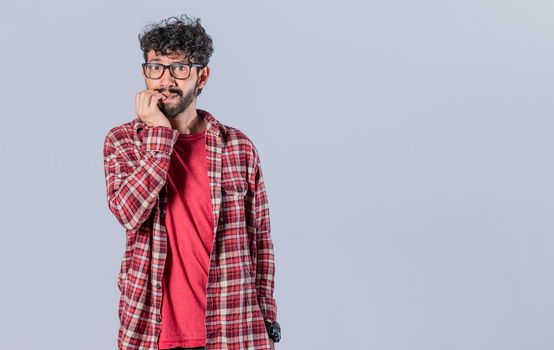 Nervous man with worried expression, bites his nails and looks anxiously. Person with worried expression biting his nails, concept of nervous man biting his nails