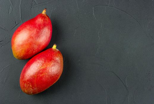 Two red delicious mango fruits on a concrete background, top view