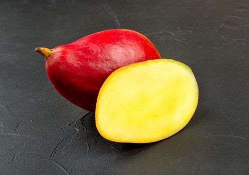 Red mango with a half on a dark background