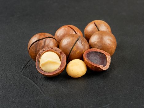 Several macadamia nuts on a dark concrete background