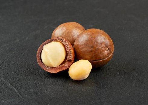 Several macadamia nuts on a dark concrete background