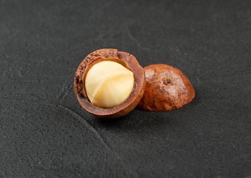 Macadamia nut split into two halves on a dark background