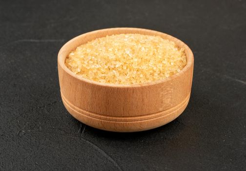 Wooden bowl with brown sugar on a concrete background