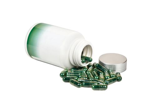 Green capsules with a plastic jar on a white background