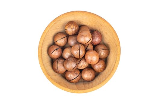 Macadamia nuts in a shell in a wooden bowl on a white background top view