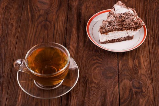 A cup of black tea with chocolate cake with cream on the table