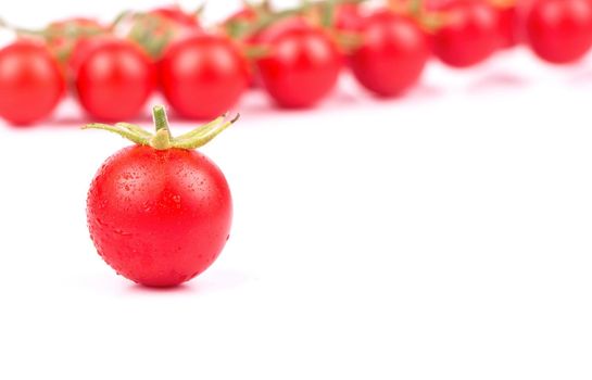 Fresh small red cherry tomatoes with drops near the sprigs on a white