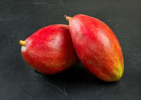 Two red delicious mango fruits on a concrete background