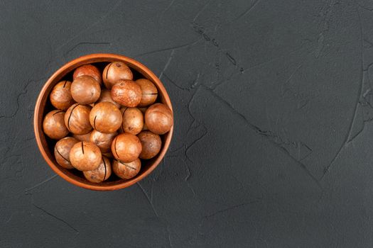 Macadamia nuts in a bowl on an empty concrete background
