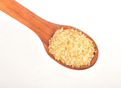 Brown sugar in a wooden spoon isolated on a white background closeup