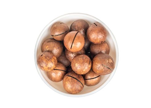 Macadamia nut in a ceramic bowl on a white background, top view