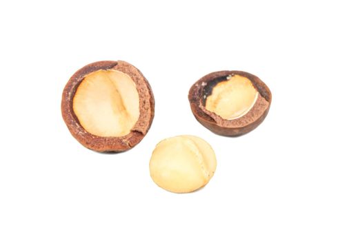 Split macadamia nuts with whole ones on a white background