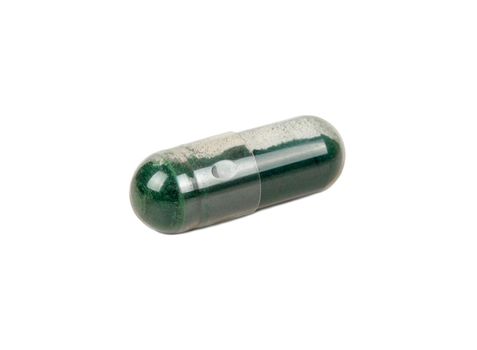 Transparent capsule with medicinal green grass isolated on a white background